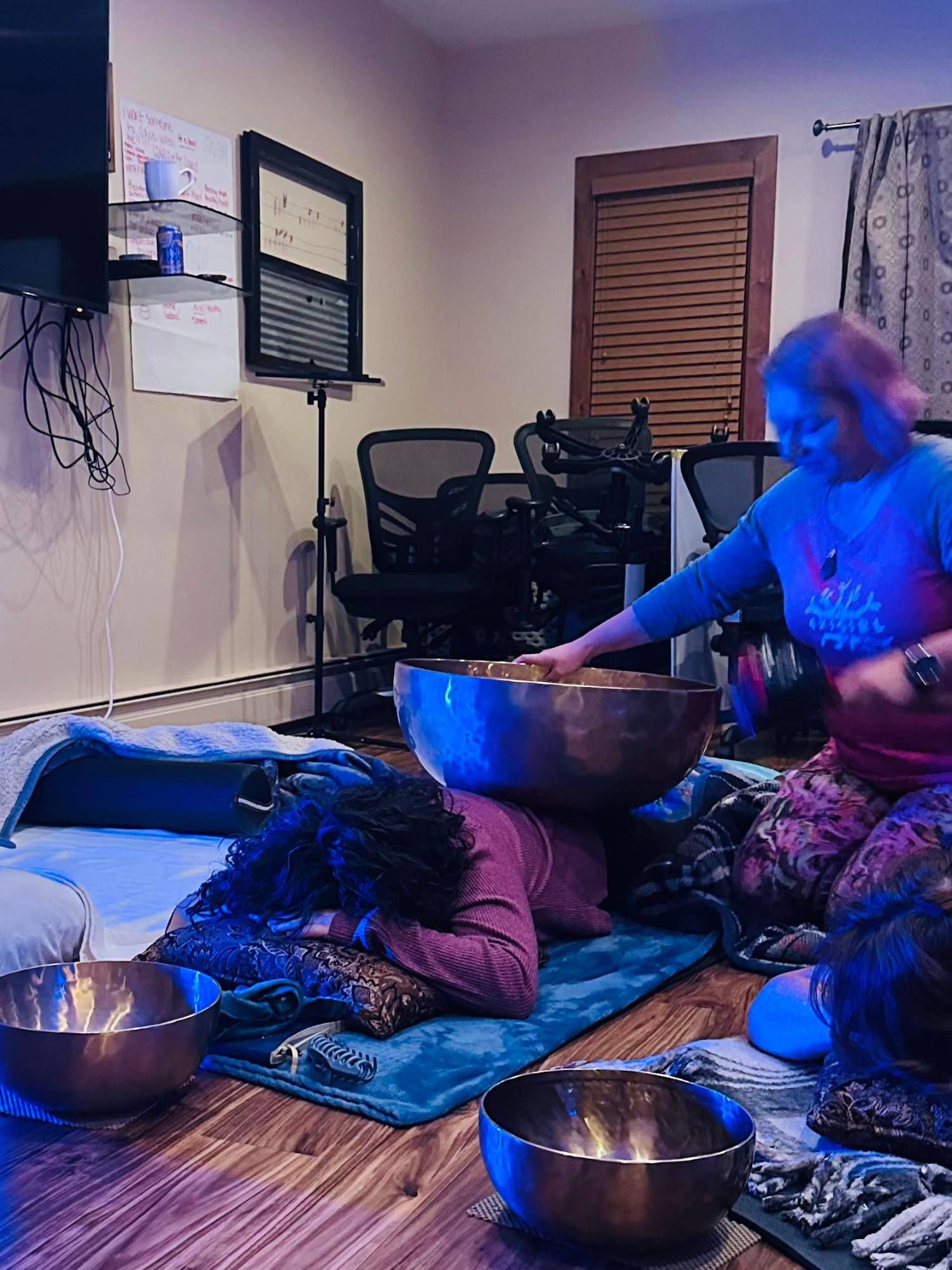 Alexandra playing a large singing bowl on a guest's back during a corporate retreat